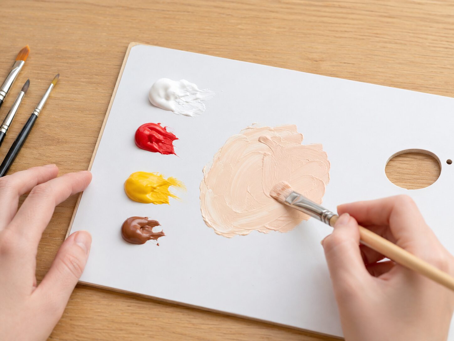 白赤黄茶色の絵の具をパレットで混ぜて肌色を作っているイメージ