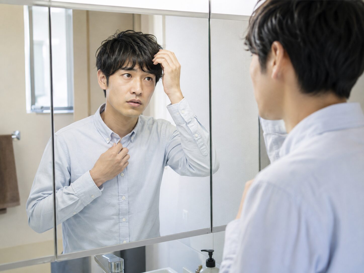 一日入浴できなかった翌朝に洗面所で前髪と衣類を確認している人物の写真
