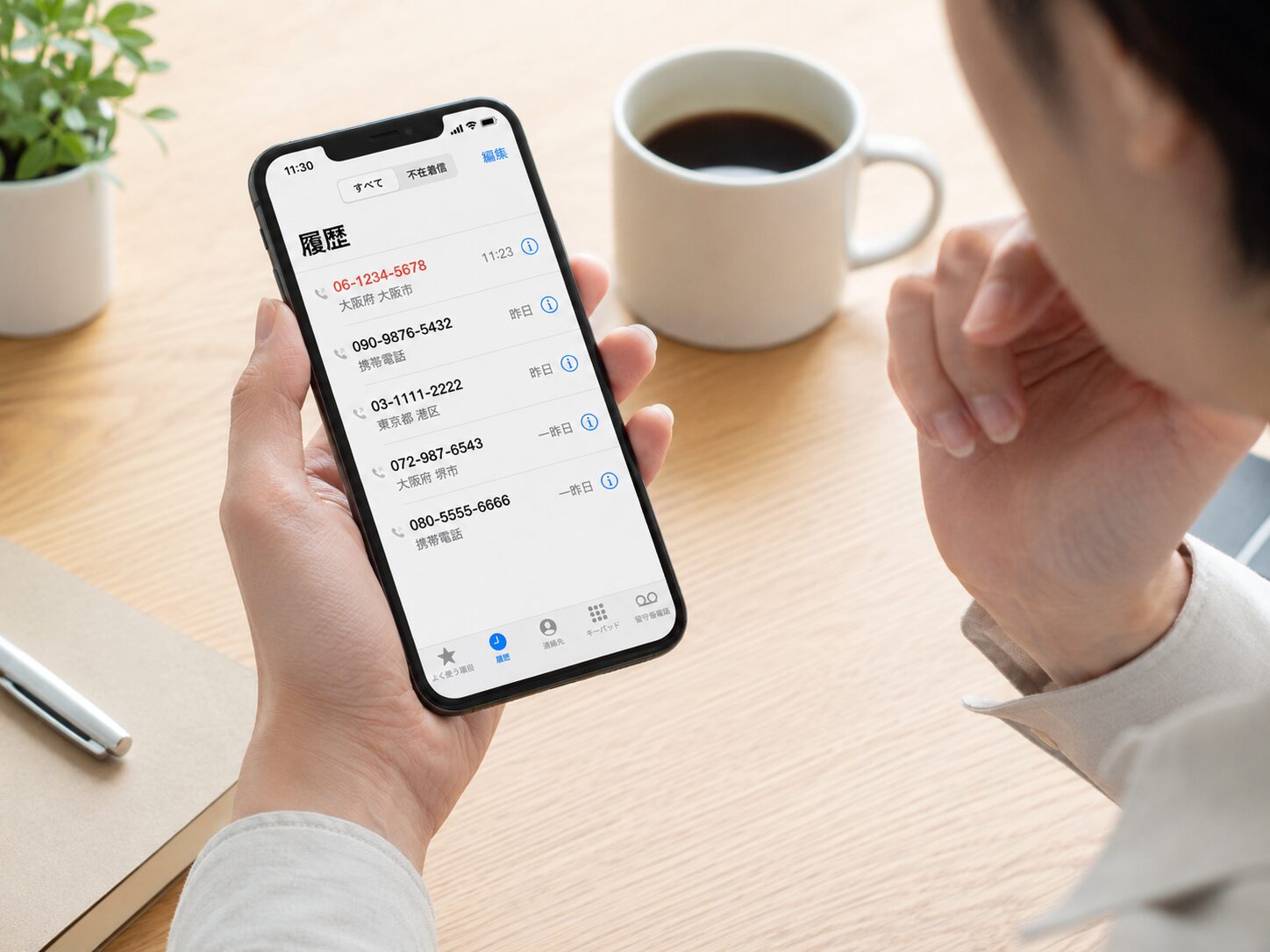 スマートフォンの着信履歴に06から始まる電話番号が表示されているか確認しているイメージ
