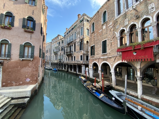 イタリアの街並みと通話している人物の合成イメージ