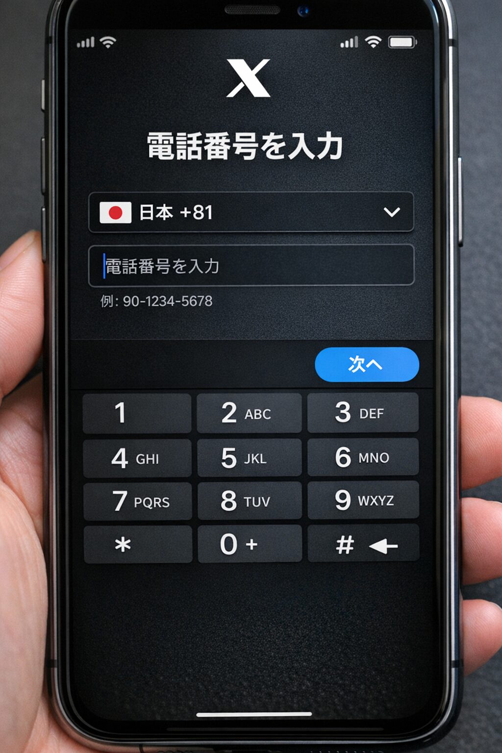 Xの電話番号入力画面をイメージした画像。国番号の選択欄と電話番号入力欄があり、日本は+81で入力方法が分かるスマートフォン画面の写真