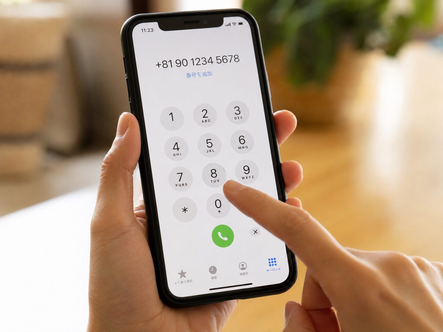 スマートフォンの電話画面に+81 90から始まる日本の携帯電話番号を入力している手元の写真