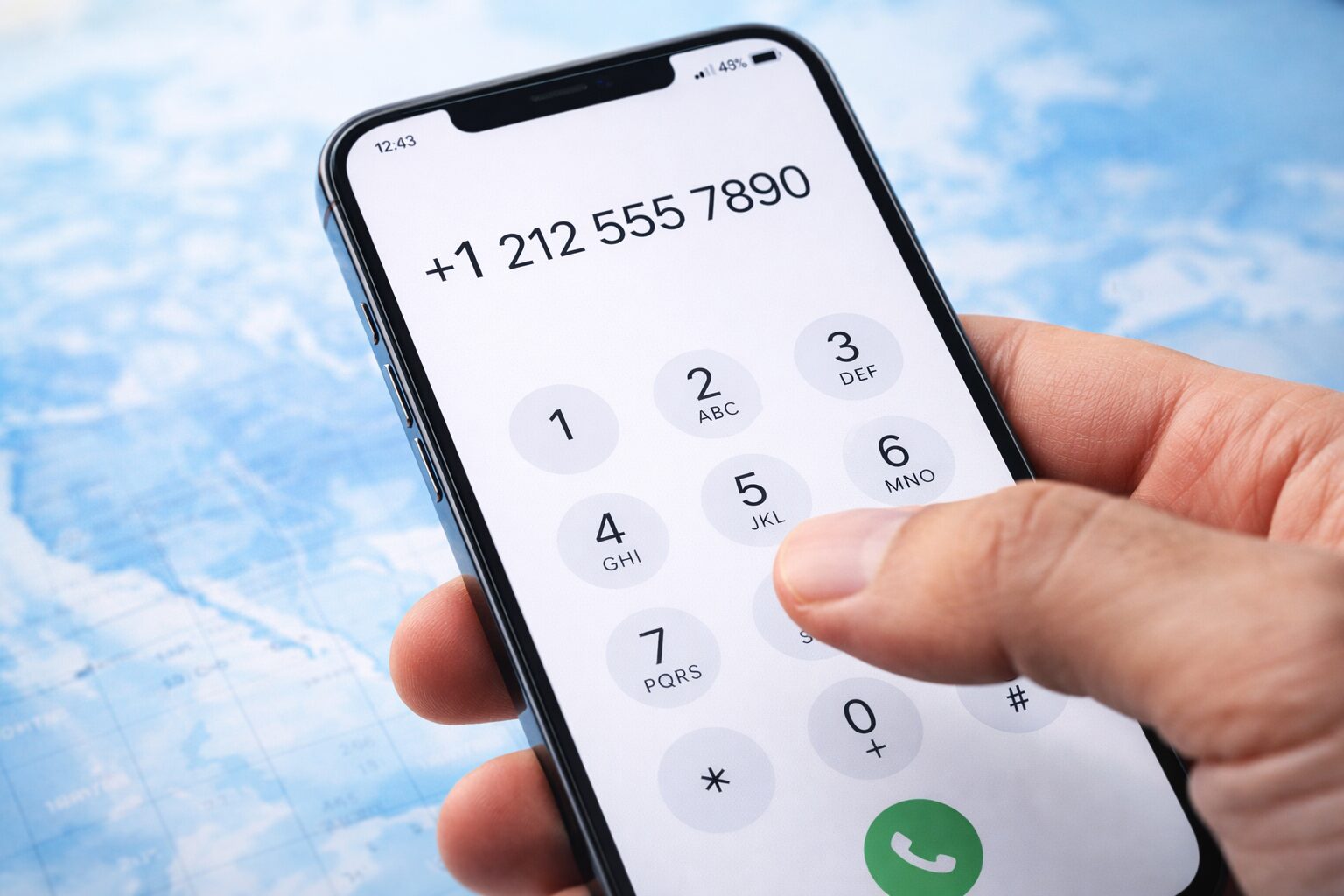 無料素材向け：スマートフォンのダイヤル画面で+1を入力している様子。国際電話のかけ方説明に使える、指先と画面が写る写真素材の指示（個人情報が写らない、架空の番号表示）
