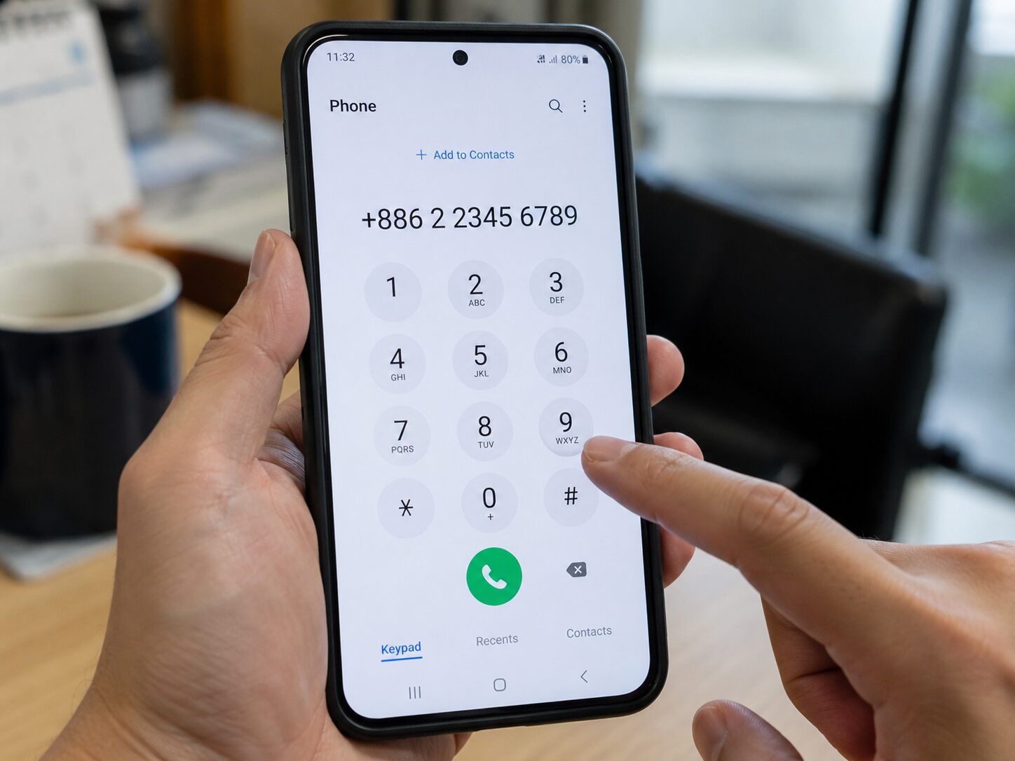スマートフォンの電話画面に+886 2から始まる台北の固定電話番号を入力している手元の写真