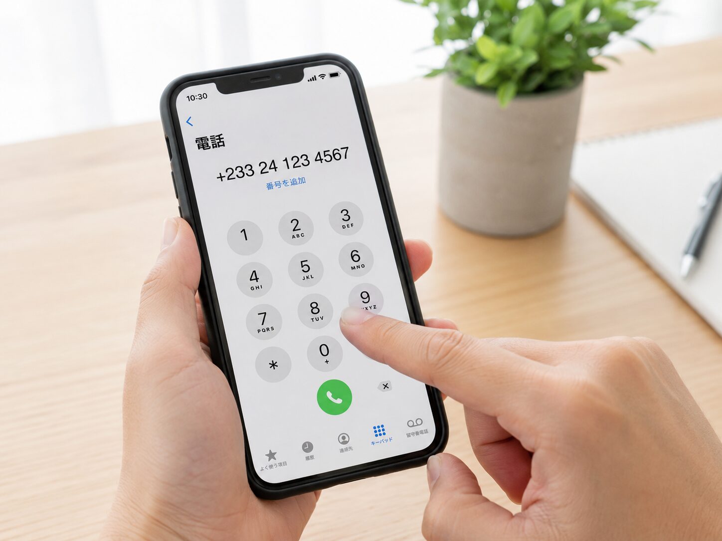スマートフォンのダイヤル画面で+233から始まるガーナの電話番号を入力している手元のイメージ