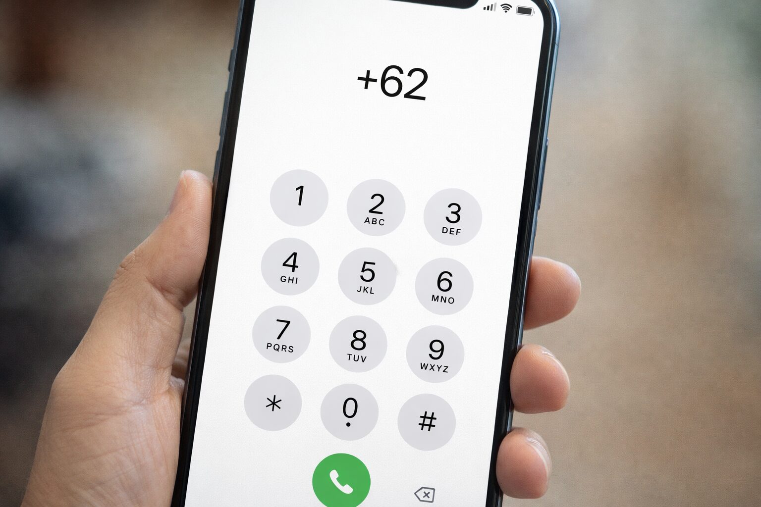 スマートフォンのダイヤル画面で+62を入力している写真イメージ（個人情報が写らない・架空番号表示の無料素材向け）