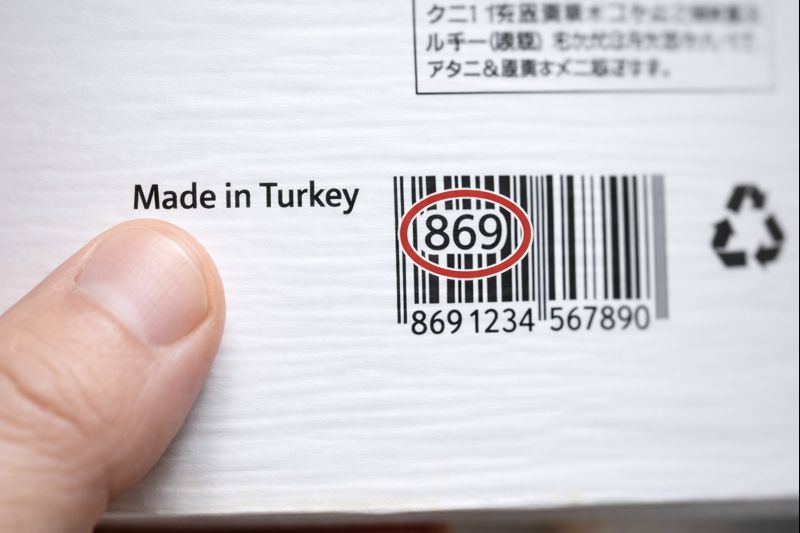 商品の原産国表示とバーコードを同時に確認しているイメージ画像（無料素材）
