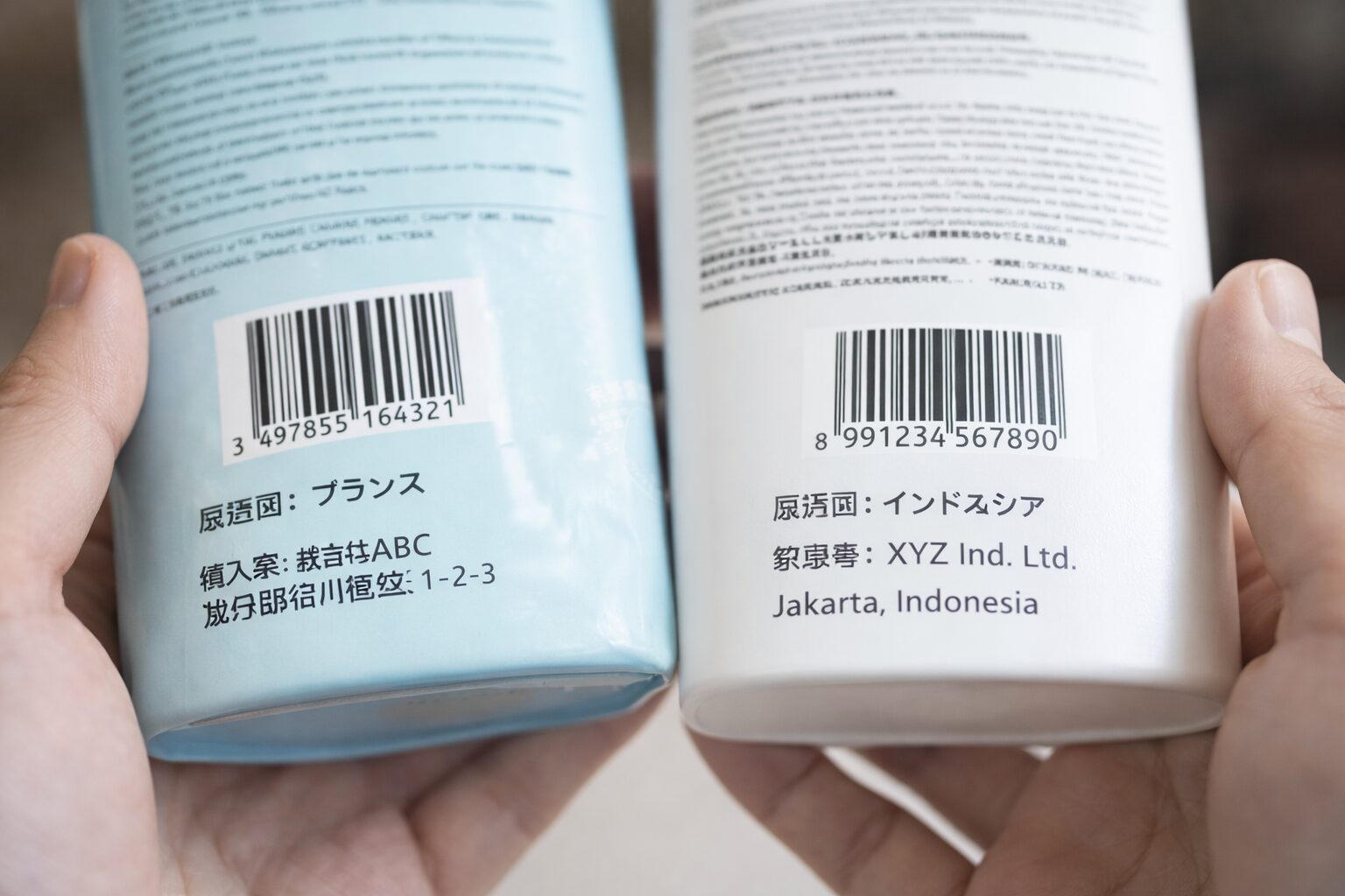 輸入食品やコスメの裏面ラベルを確認している様子の無料写真素材。バーコードだけでなく原産国表示、輸入者表示、製造者表示を見比べている場面が伝わる画像を中央寄せで使用。