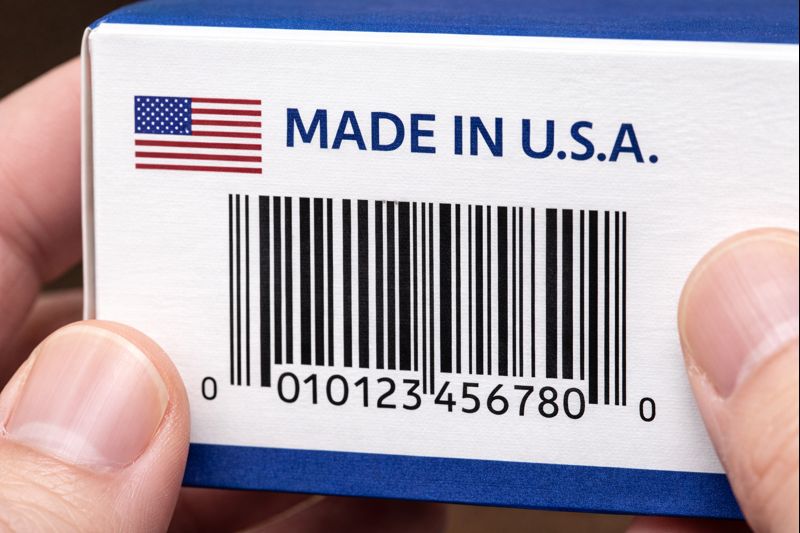 商品の原産国表示（Made in 表記）とバーコードを同時に確認しているイメージ画像（無料素材）