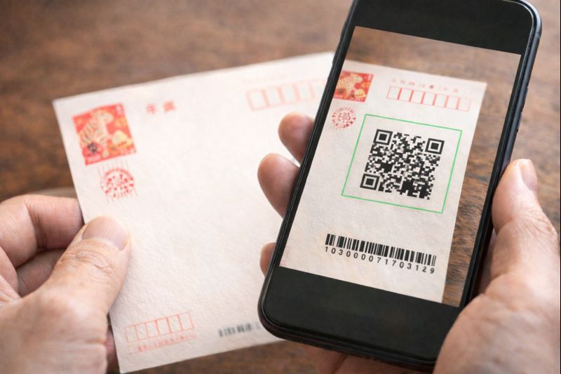 年賀状のQRコードをスマートフォンで読み取る手元のイメージ（公開設定の注意を促す無料素材）
