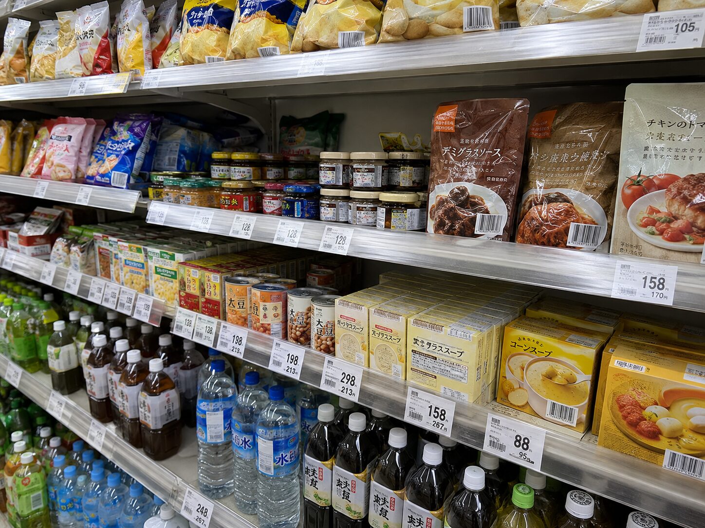 スーパーの商品棚にさまざまな商品が並び、それぞれのパッケージにJANバーコードが表示されている写真