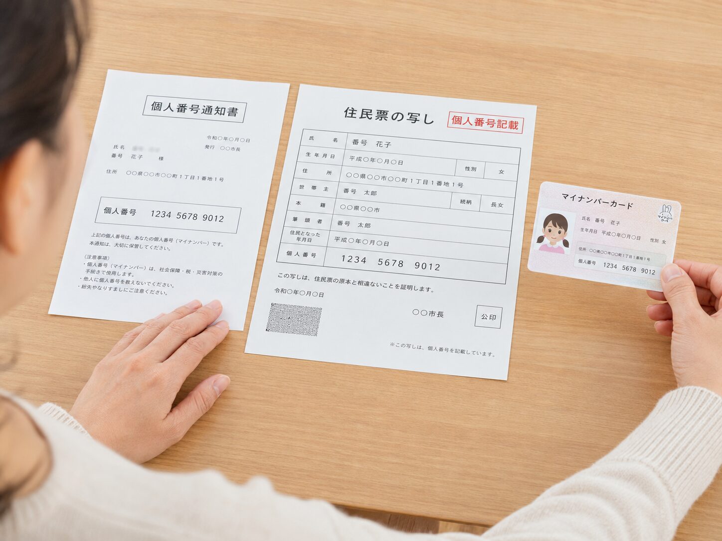 保護者が個人番号通知書とマイナンバー記載の住民票と子どものマイナンバーカードを並べて確認している写真