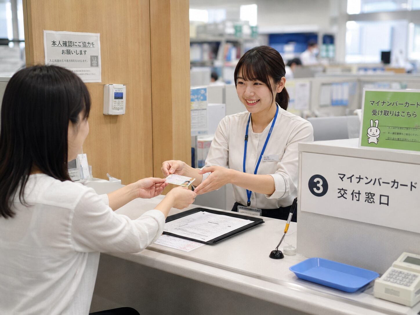 市区町村の窓口でマイナンバーカードの受け取り手続きをしているイメージ。無料写真素材で、役所の受付、書類確認、本人確認の雰囲気が分かる画像を使用する