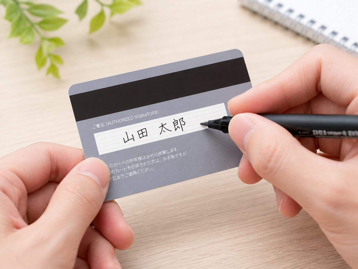 クレジットカード裏面の署名欄に油性ペンで丁寧にサインしているイメージ