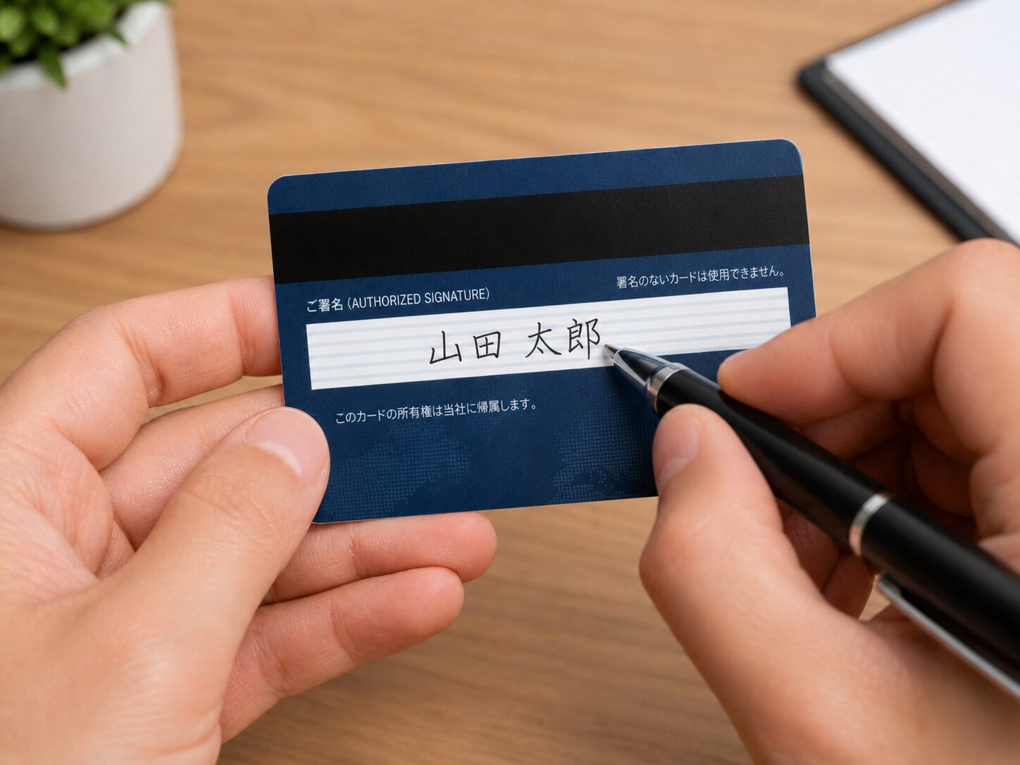 クレジットカード裏面の署名欄に本人がサインしているイメージ